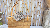 Front view of the handwoven rattan square tote showing the batik drawstring liner and leather handles