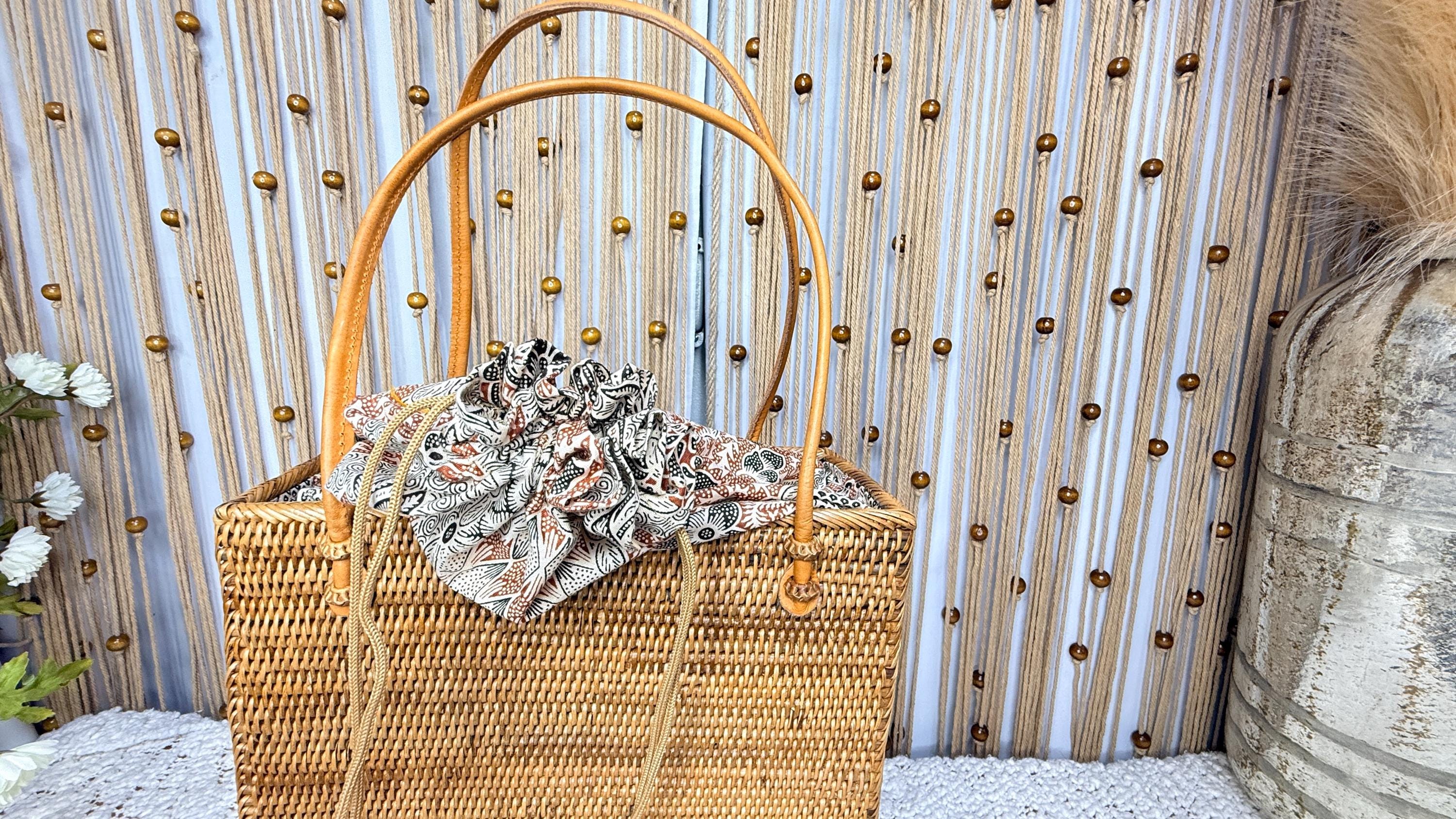 Front view of the handwoven rattan square tote showing the batik drawstring liner and leather handles