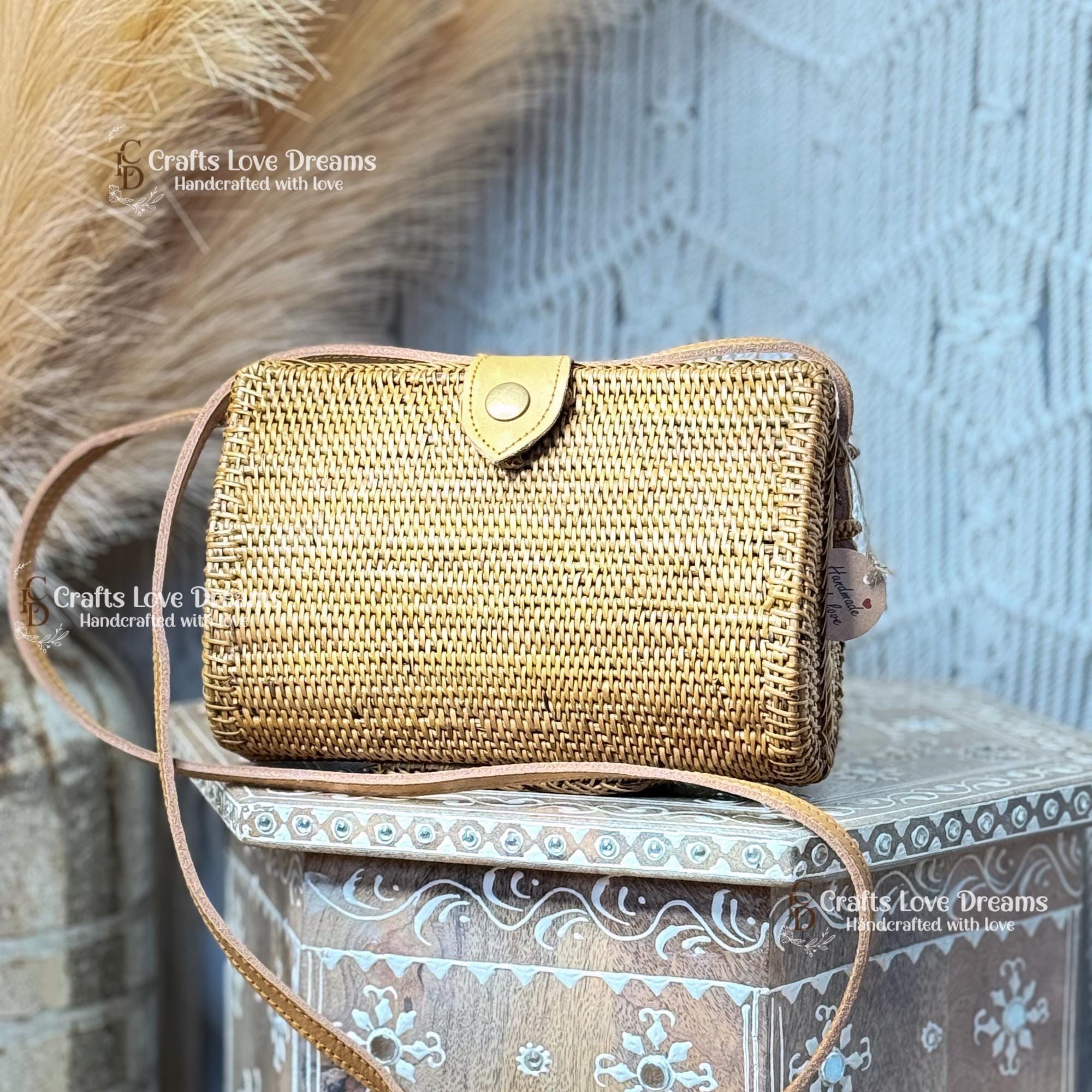 A woven straw bag with a leather strap is displayed against a blue and white patterned background.