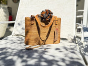 A woven straw handbag with a colorful scarf tied around the handle, placed on a white chair.