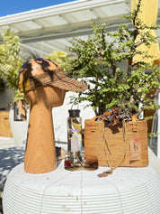 a variety of items, including a hat, sunglasses, a woven bag, and a bottle, arranged on a white table.