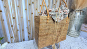 Handwoven rattan square tote with the batik drawstring liner closed, shown with the Crafts Love Dreams hang tag