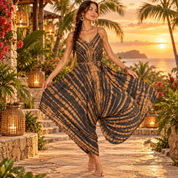 A woman in a tie-dye dress stands on a stone path, surrounded by tropical plants and lanterns, with a sunset in the background.