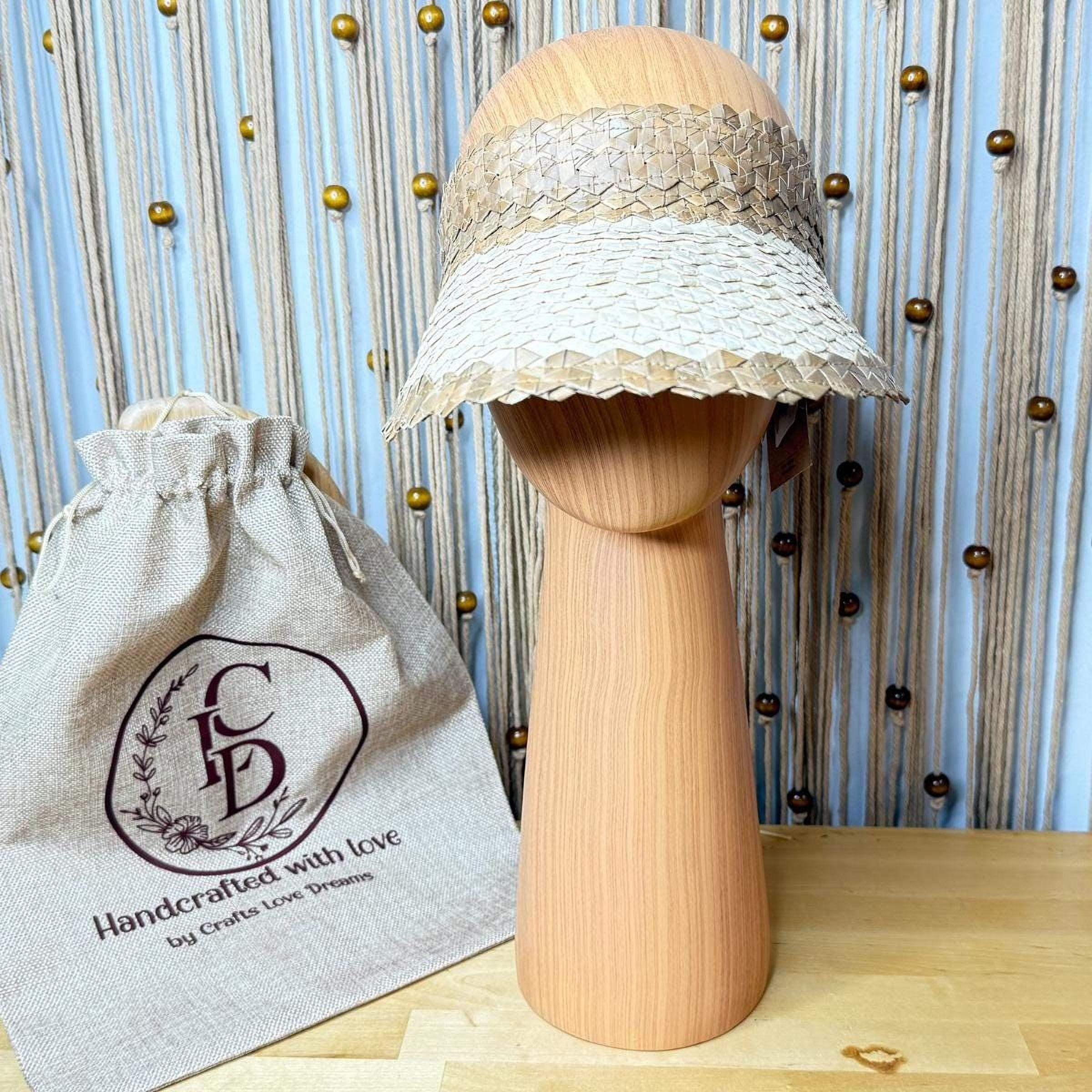 a straw hat on a wooden mannequin head, with a beige drawstring bag with a logo next to it.