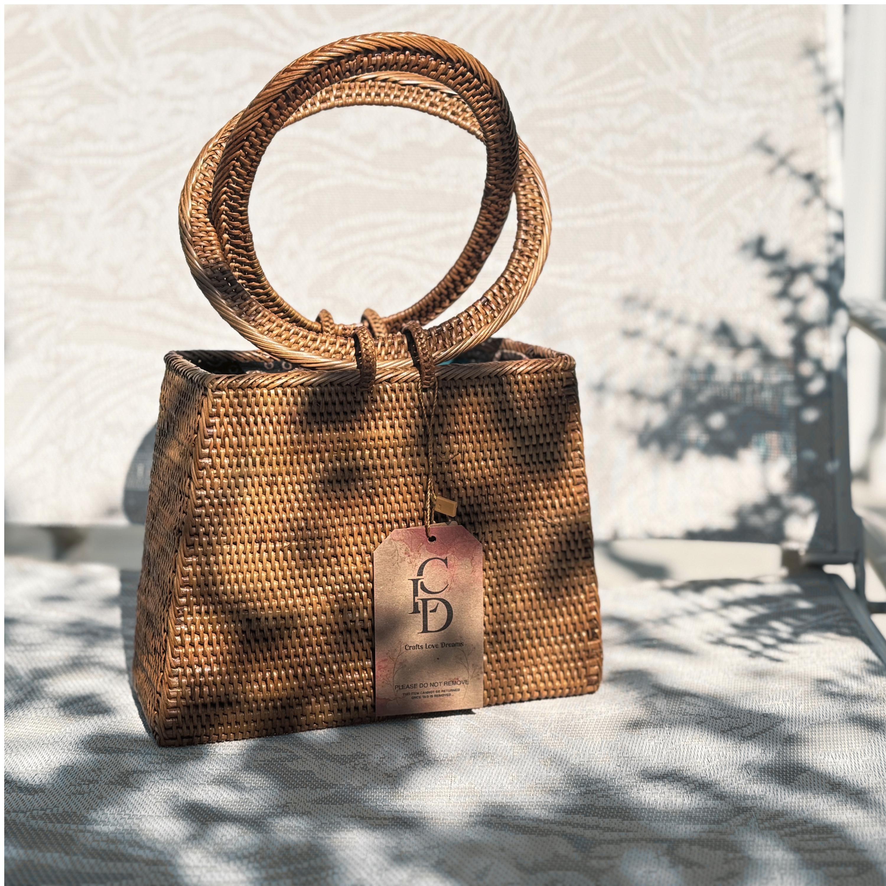 A brown woven handbag with a round handle and a tag displaying the letters "CD" is placed on a white surface against a patterned wall.