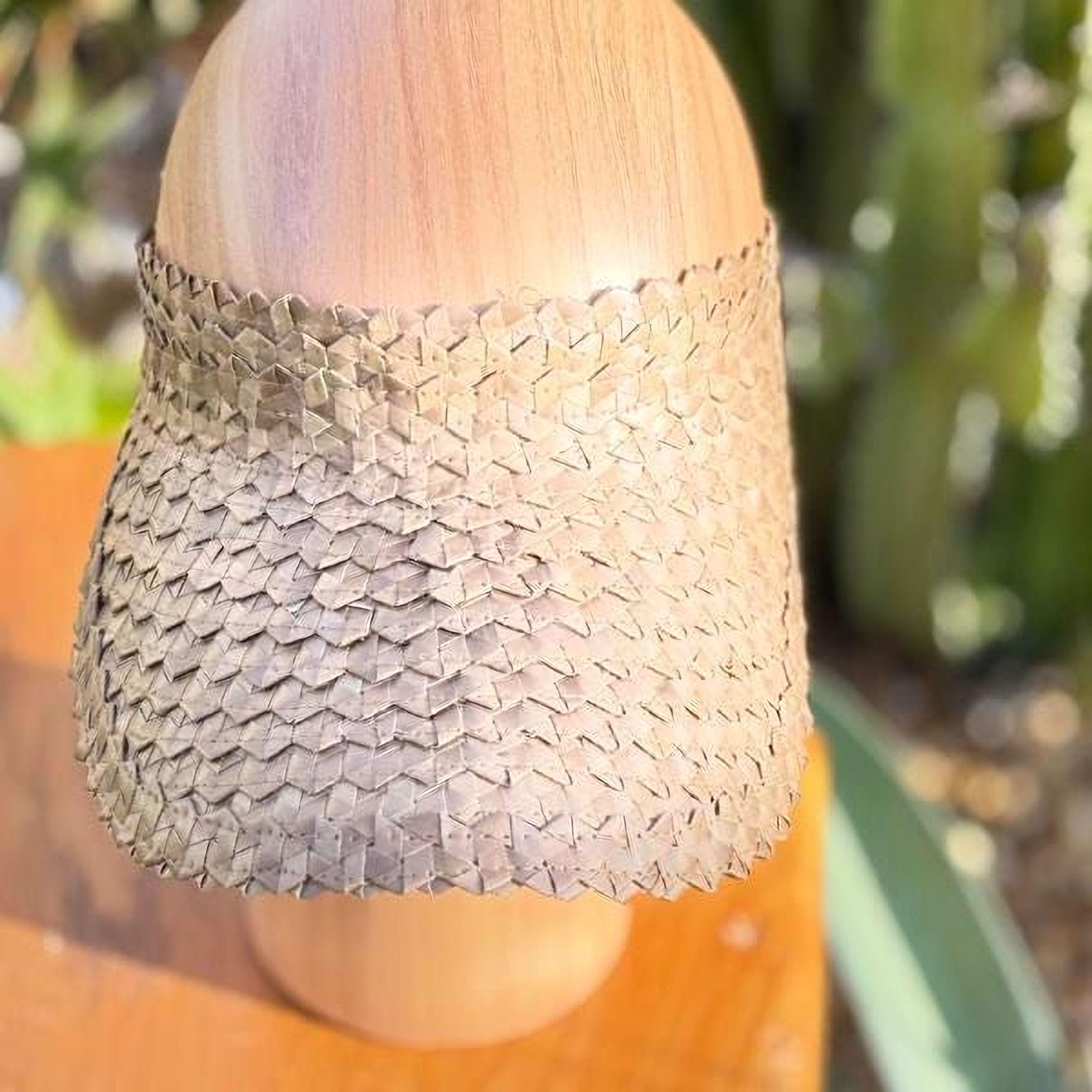 A wooden headband with a woven pattern is displayed on a wooden surface.