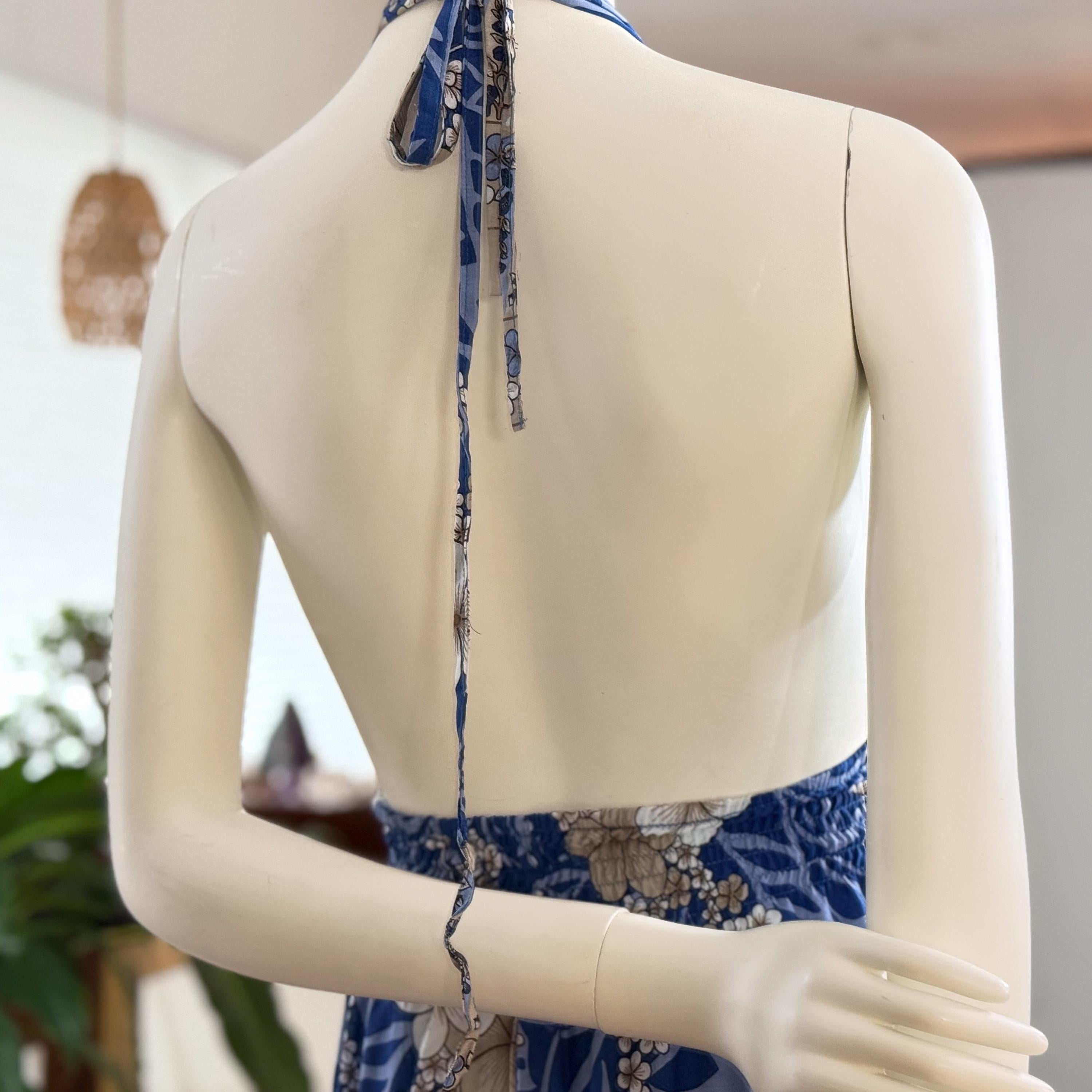 A mannequin wearing a blue and white floral dress with a blue ribbon tied around the neckline.