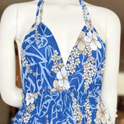 A mannequin wearing a blue and white floral print dress with a halter neckline and a ruffle detail at the bottom.