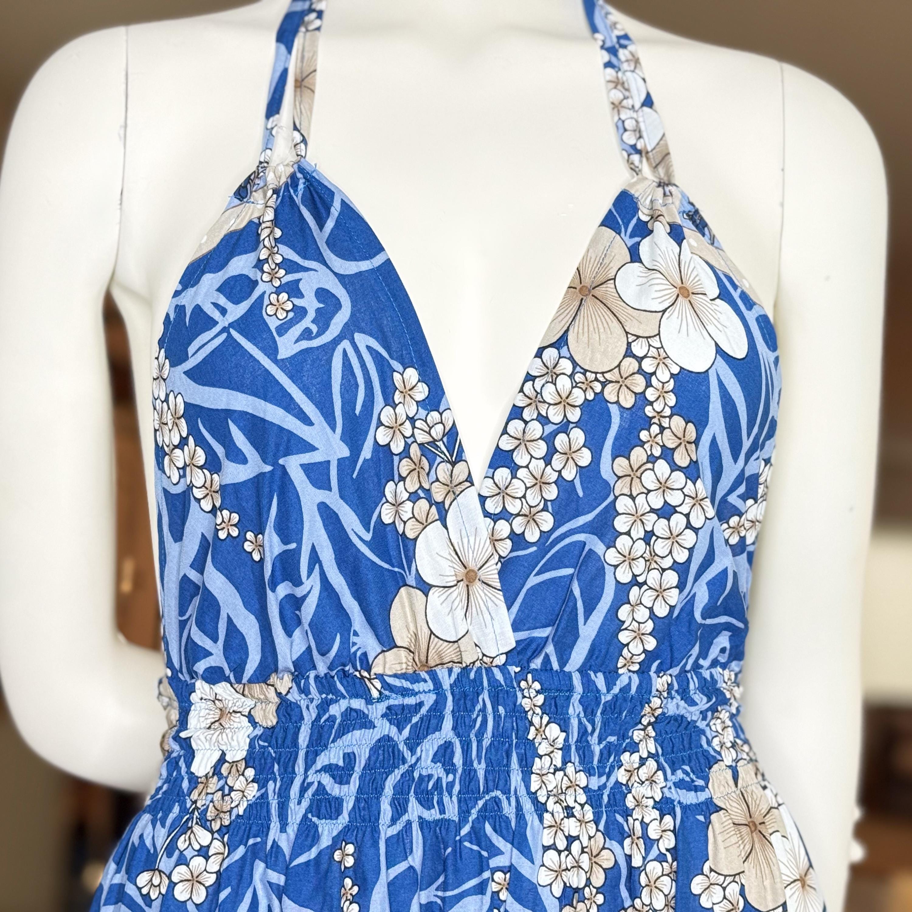 A mannequin wearing a blue and white floral print dress with a halter neckline and a ruffle detail at the bottom.