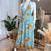 A mannequin wearing a blue and yellow floral print dress with a halter neckline and a halter top, displayed in a clothing store.
