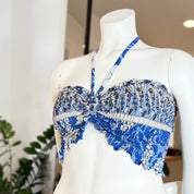 A mannequin wearing a blue and white floral print top with a ruched neckline and a halter neckline.