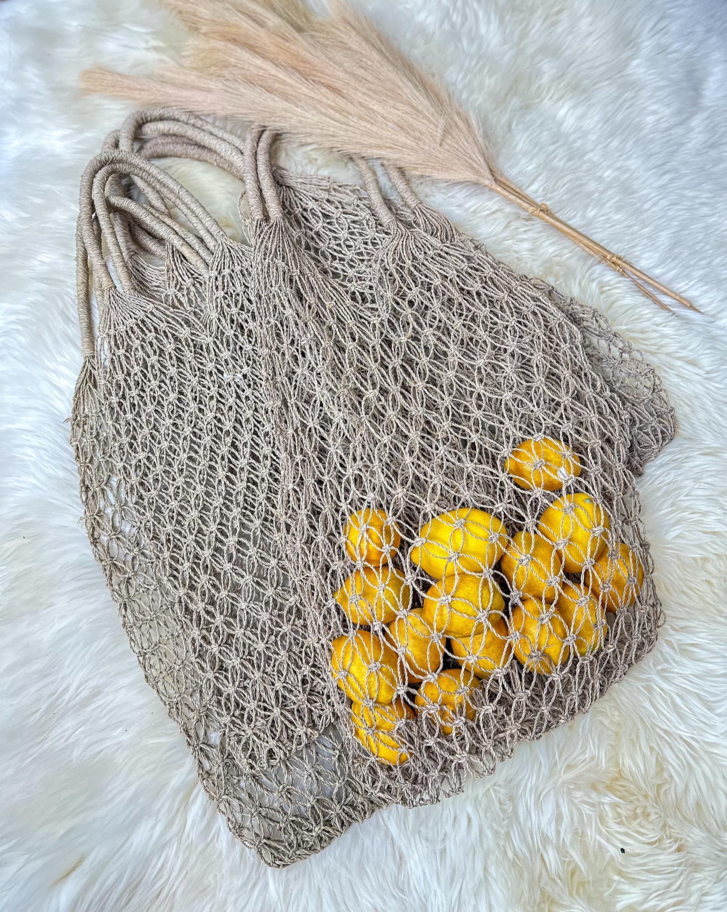 A beige mesh bag filled with bright yellow lemons rests on a white furry surface.