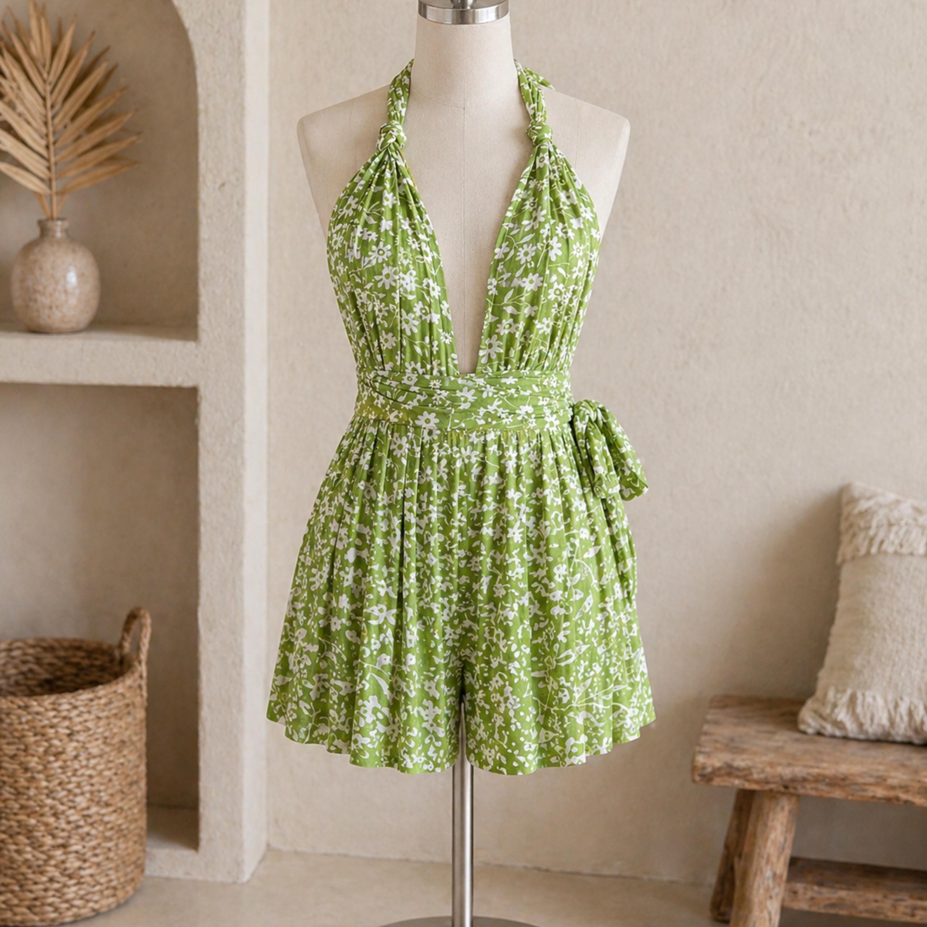A mannequin wearing a green floral print dress with a halter neckline and a wrap-style waistband.