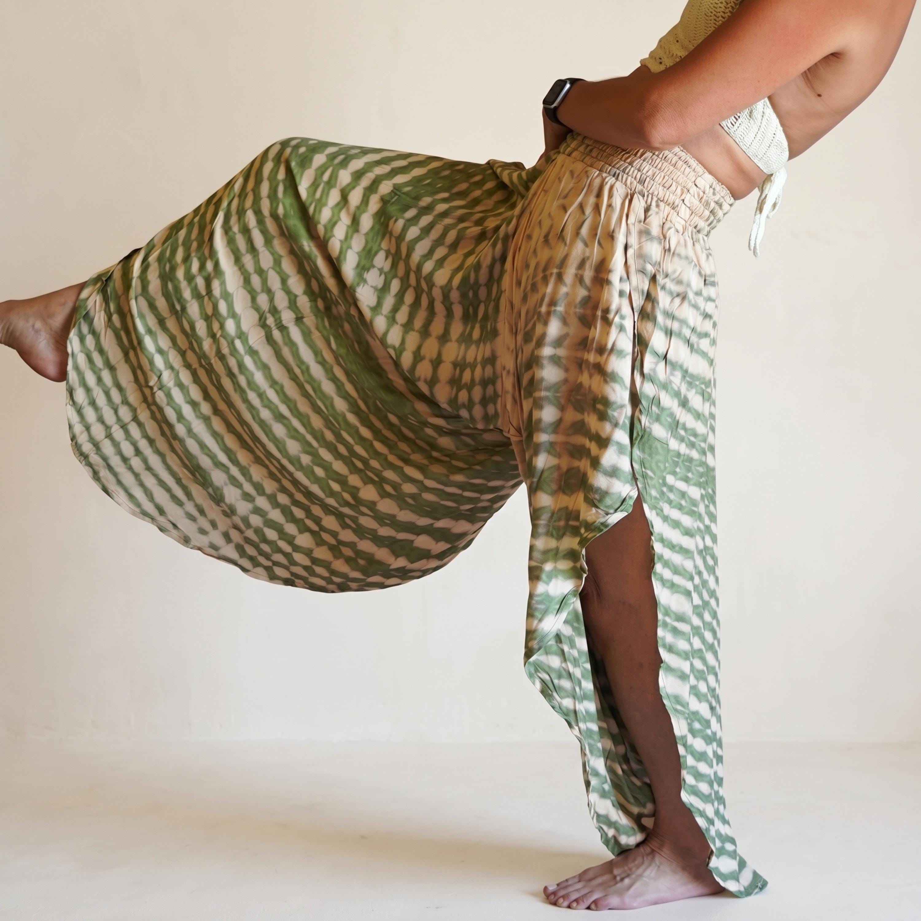 A woman wearing a green and white patterned skirt is striking a pose with one leg extended and the other bent at the knee.