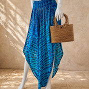 A mannequin wearing a blue and black patterned skirt and holding a woven straw bag.