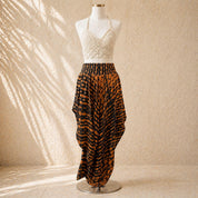 A mannequin wearing a white lace top and a long, flowing skirt with a bold, black and orange pattern.
