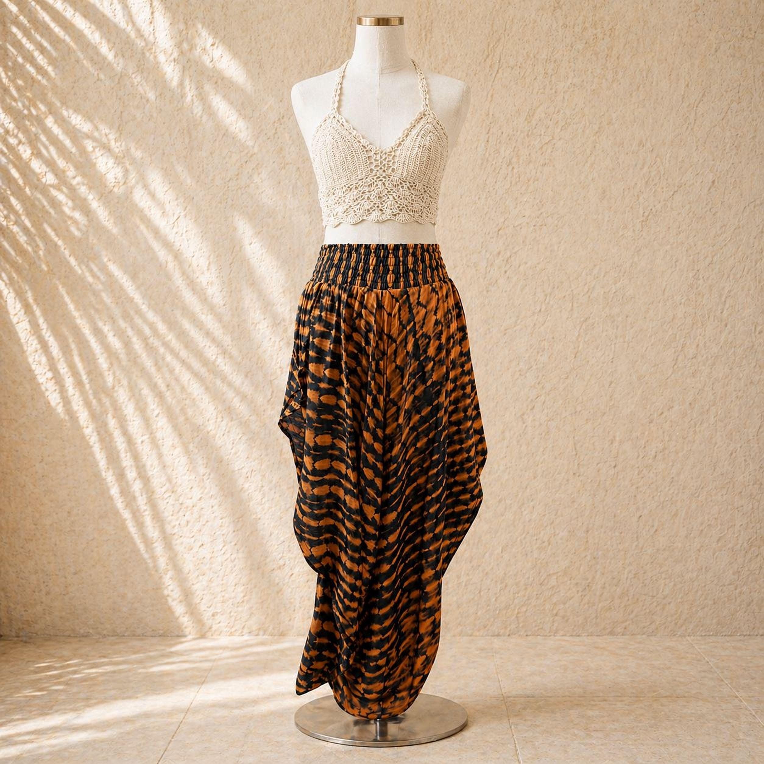 A mannequin wearing a white lace top and a long, flowing skirt with a bold, black and orange pattern.