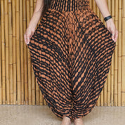A woman wearing a colorful, patterned skirt stands in front of a bamboo wall.
