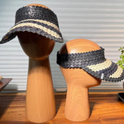 two wooden mannequin heads wearing black and white striped visors.