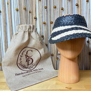 a wooden headless hat and a burlap bag with a logo, placed on a wooden surface against a background with wooden strings and beads.