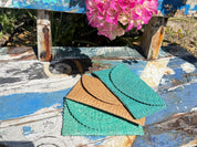 a wooden bench with a blue and white paint, a pink flower, and two folded green and brown bags or purses placed on it.