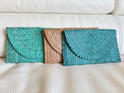 Three colorful handbags are placed on a white couch.