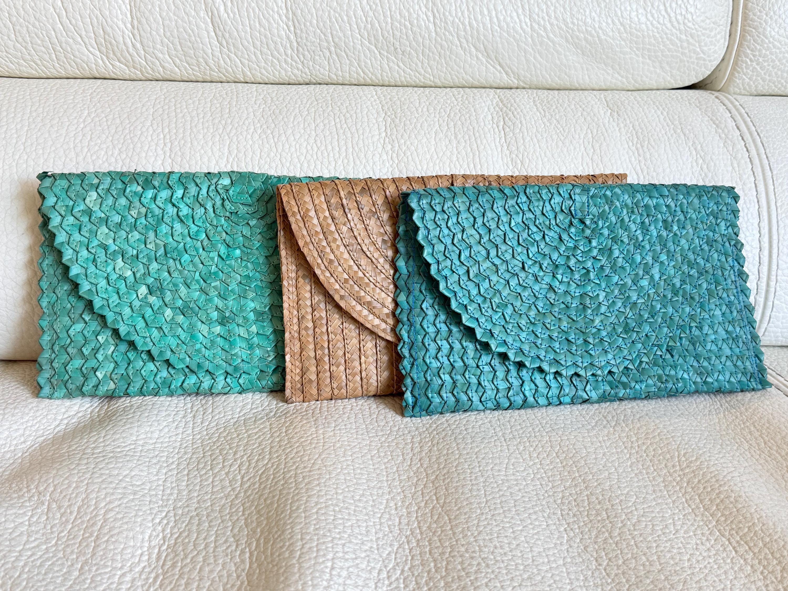 Three colorful handbags are placed on a white couch.