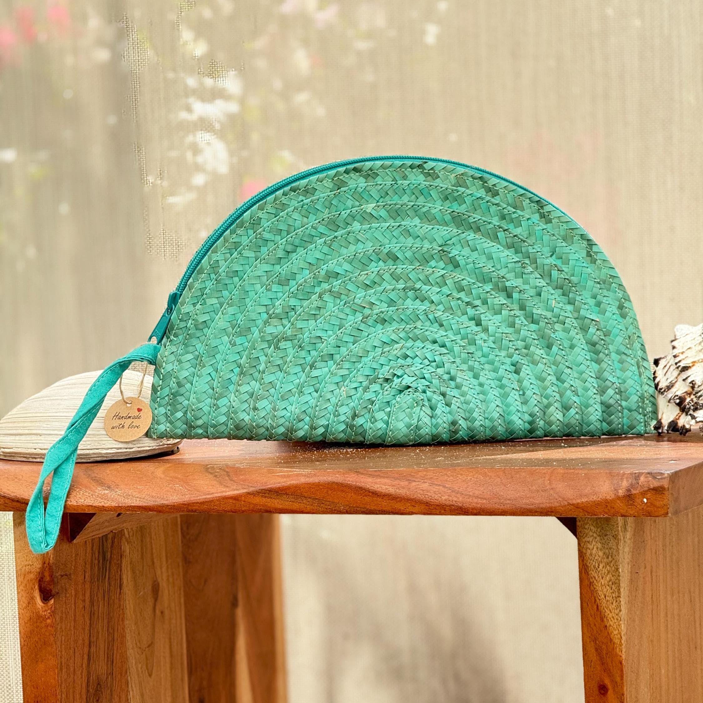 A turquoise woven handbag with a zipper closure is placed on a wooden table.