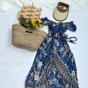 a blue floral dress, a straw hat, a woven basket, and a sunflower, all arranged on a white background.