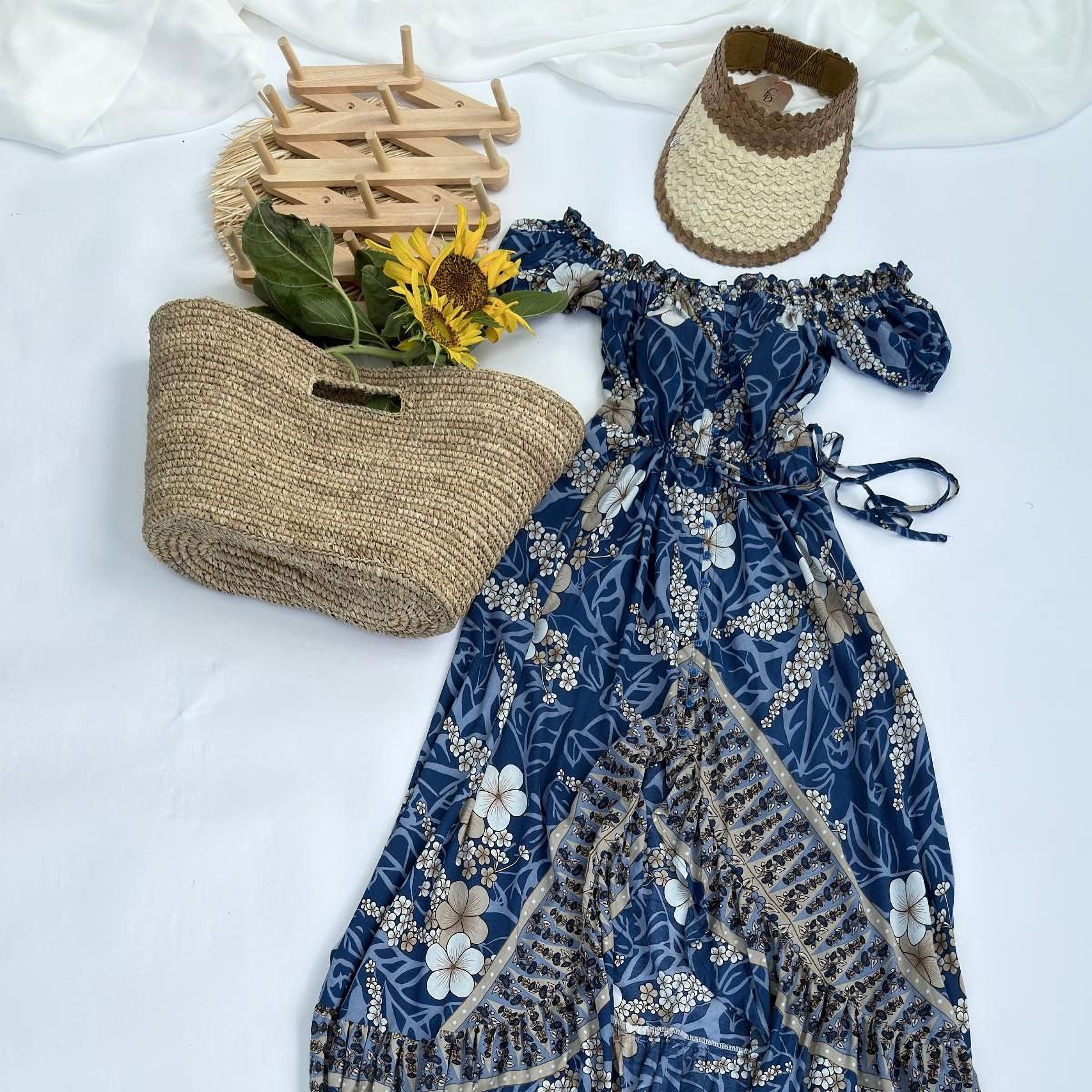a blue floral dress, a straw hat, a woven basket, and a sunflower, all arranged on a white background.