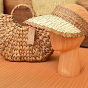 a straw hat and a woven handbag placed on a wooden surface.