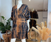 A mannequin wearing a tie-dye dress with a black and orange pattern, displayed in a clothing store.