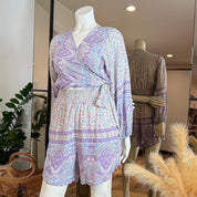 A mannequin wearing a purple and white patterned wrap top and shorts, displayed in a clothing store.