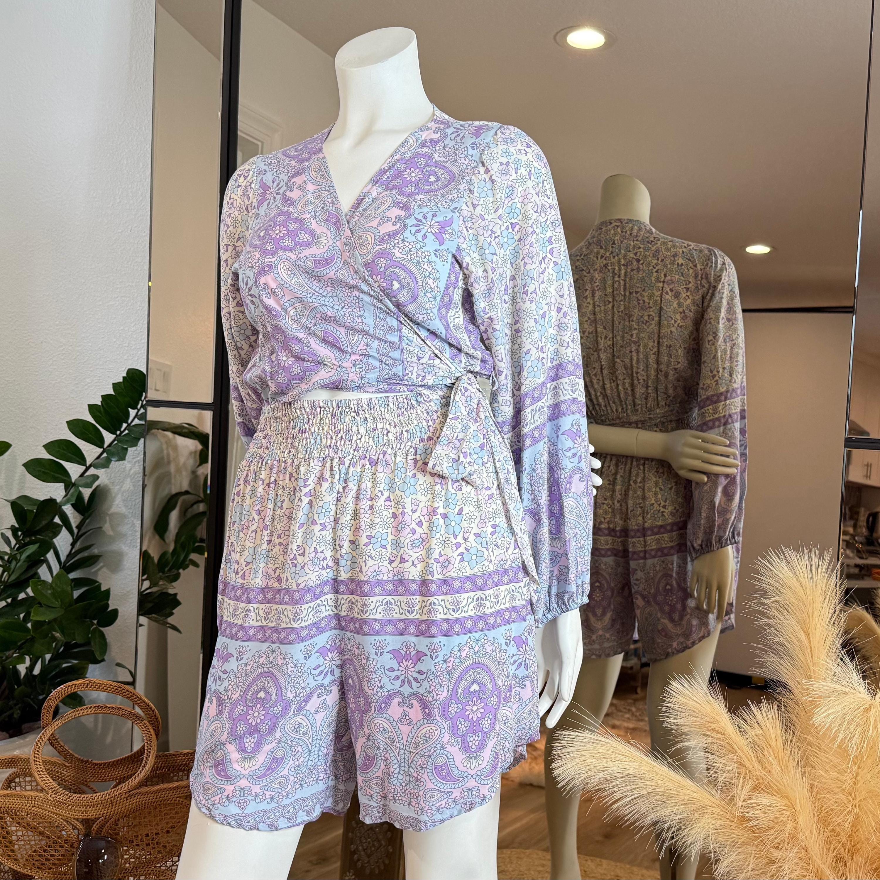 A mannequin wearing a purple and white patterned wrap top and shorts, displayed in a clothing store.