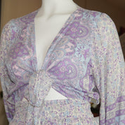 A mannequin wearing a purple and white patterned blouse with a tie waist, paired with a skirt.