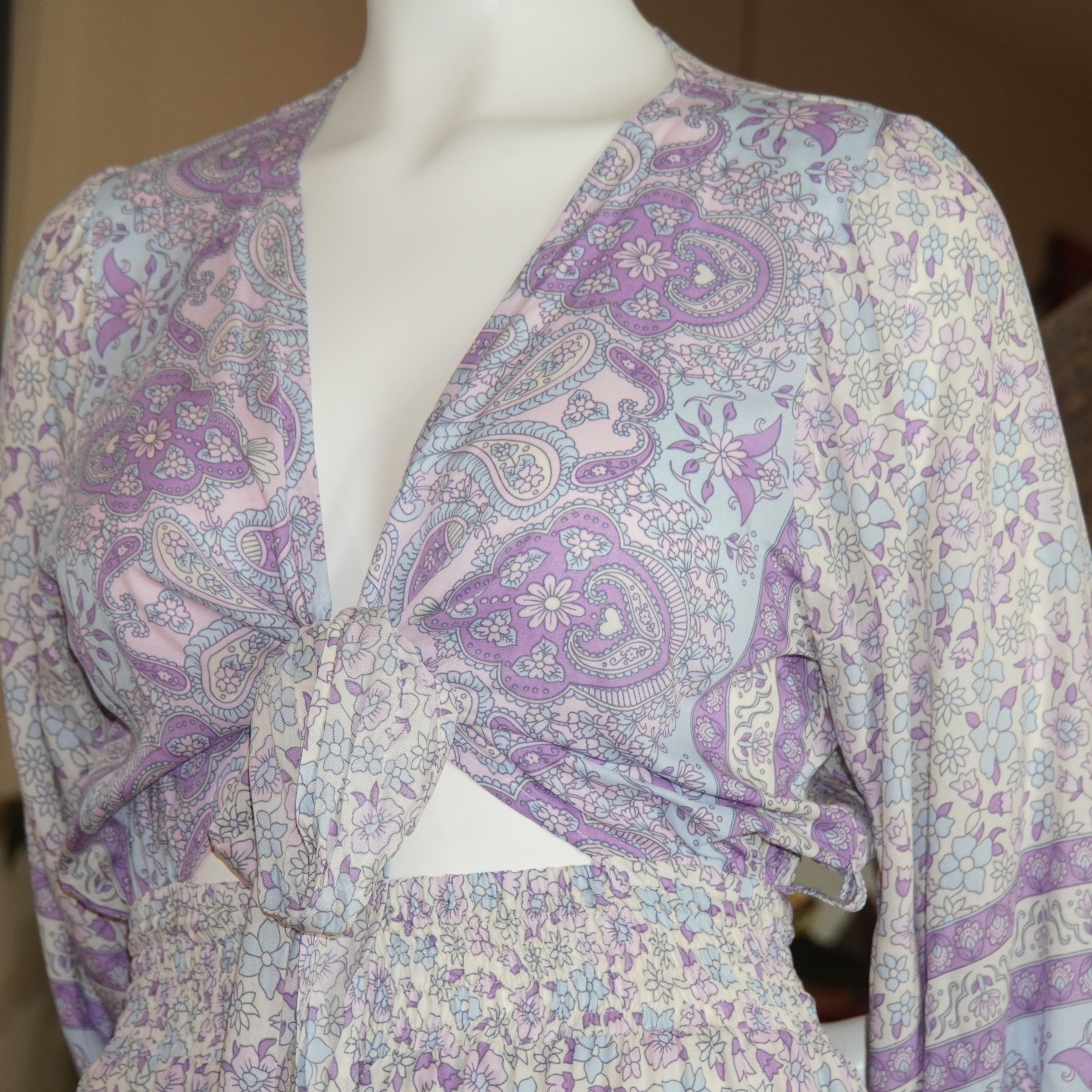 A mannequin wearing a purple and white patterned blouse with a tie waist, paired with a skirt.