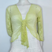 A mannequin wearing a lime green, tie-front jacket with a white skirt.