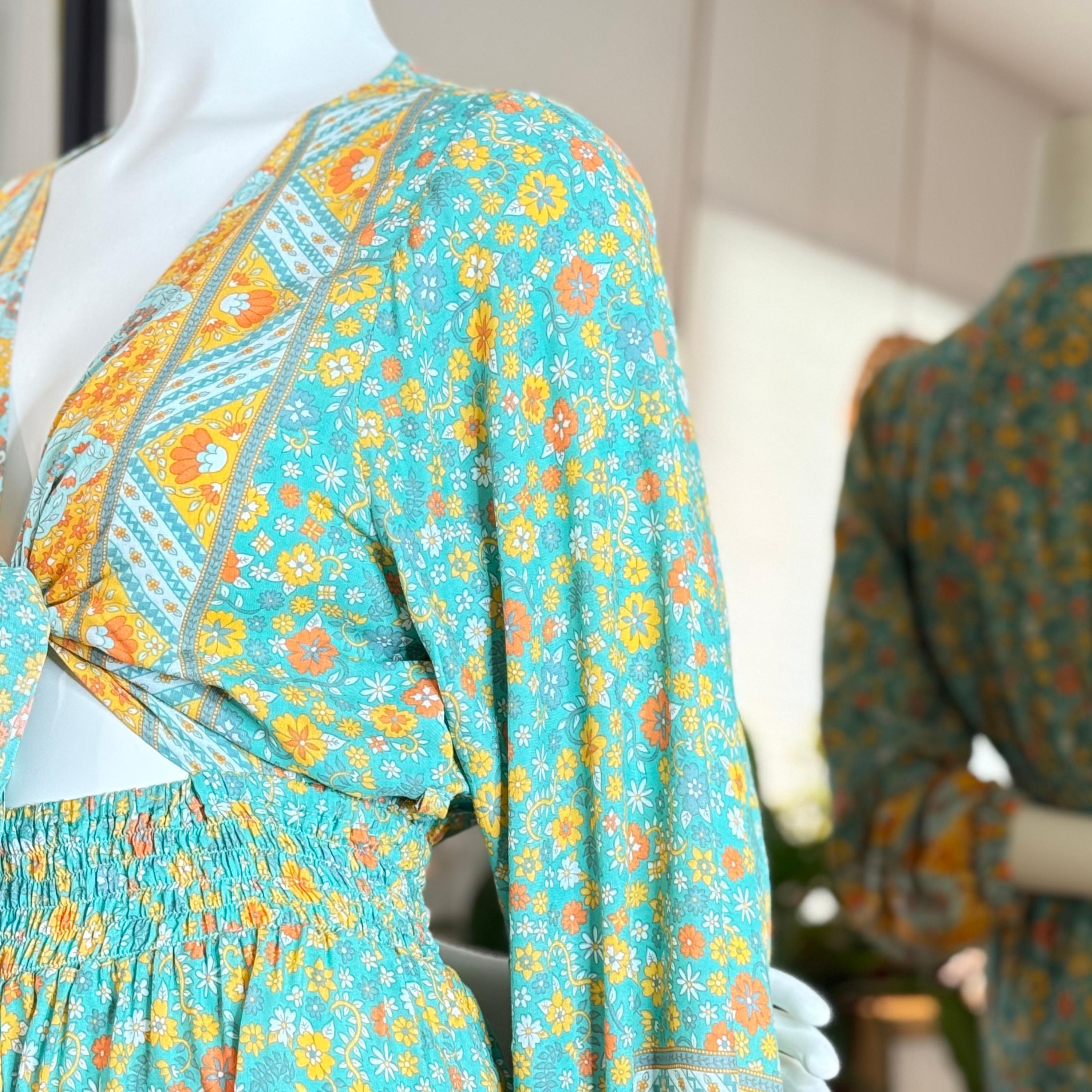 A mannequin wearing a turquoise and yellow floral print dress with a tie waist, displayed in a retail setting.
