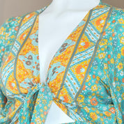 A colorful, tie-front top with a floral pattern in shades of green, yellow, and orange.