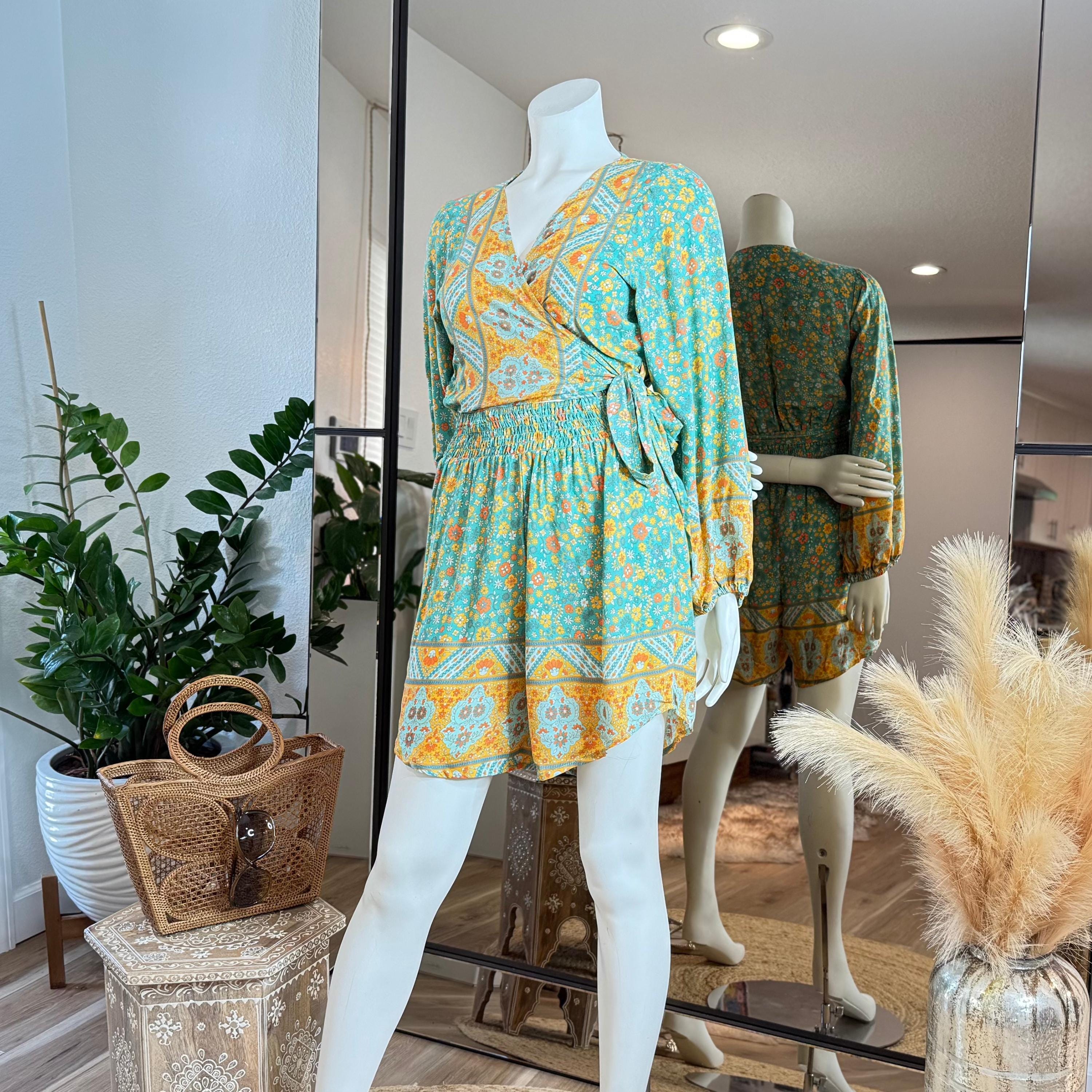 A mannequin wearing a colorful wrap-style dress with a floral pattern, displayed in a clothing store.