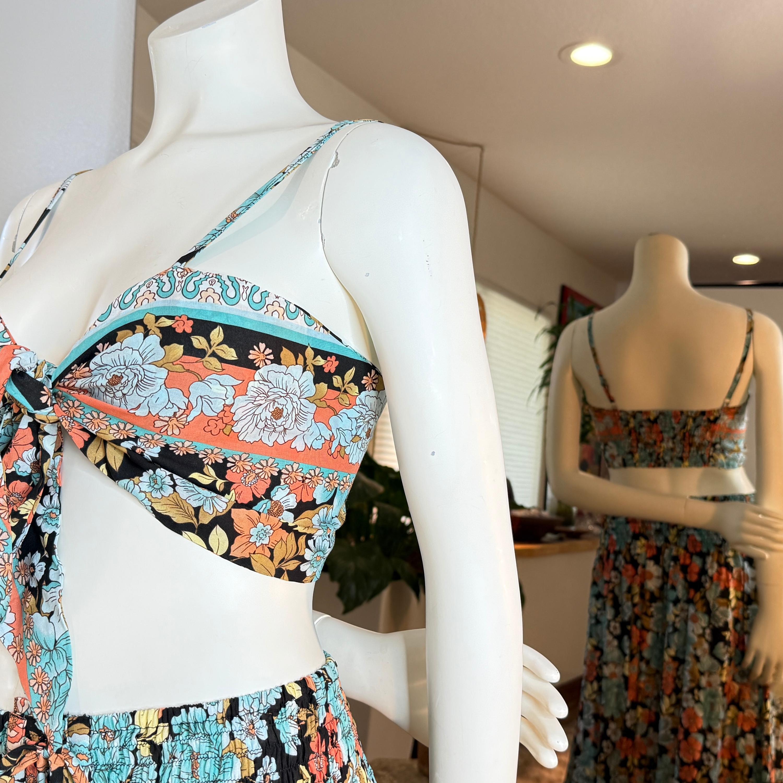 A mannequin wearing a colorful floral print top and skirt, with a tie waist, displayed in a clothing store.