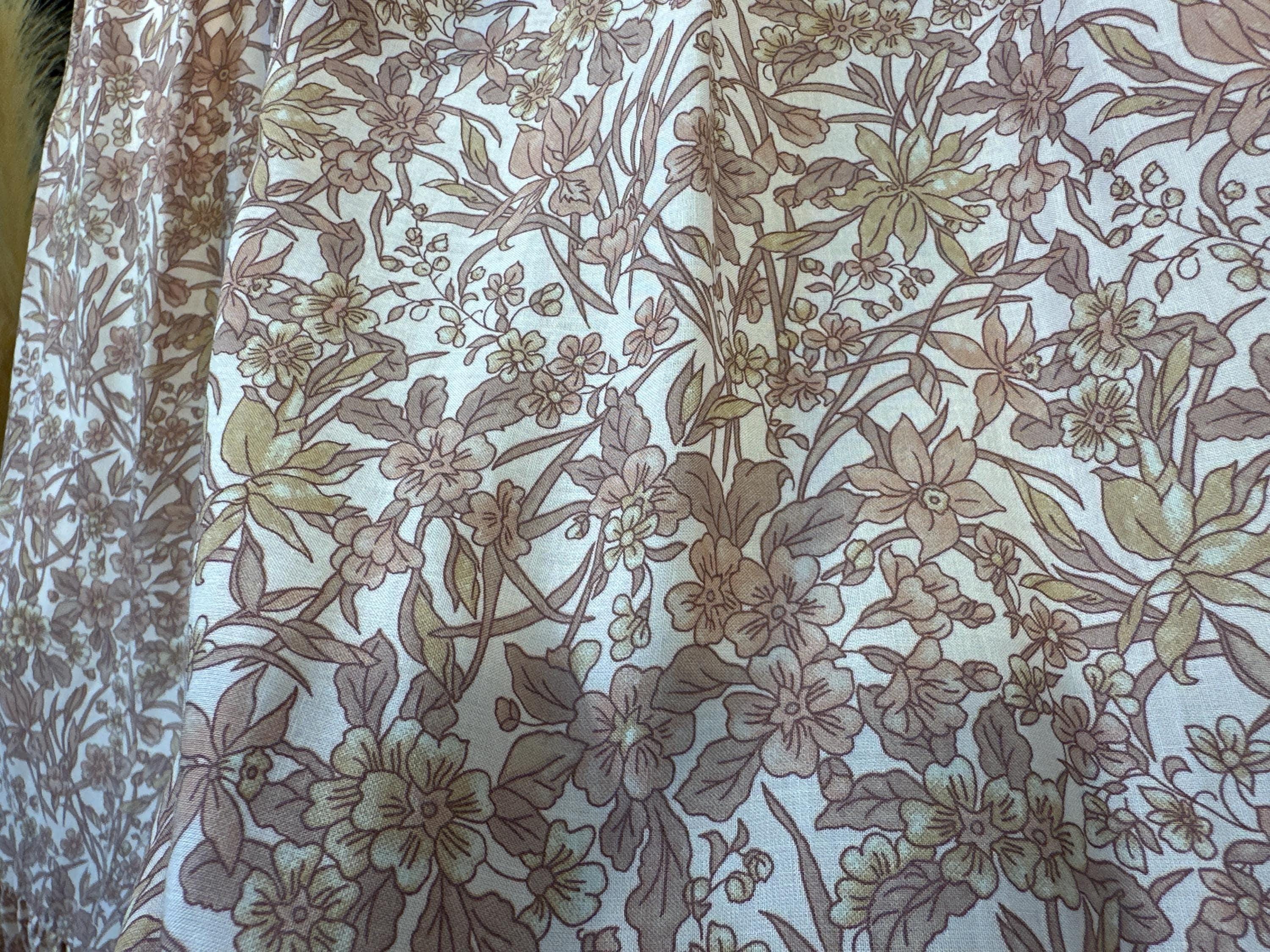 a close-up view of a fabric with a floral pattern, featuring various shades of brown and beige flowers and leaves.