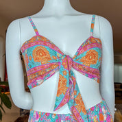 A mannequin wearing a colorful, tie-front bikini top with a floral pattern.