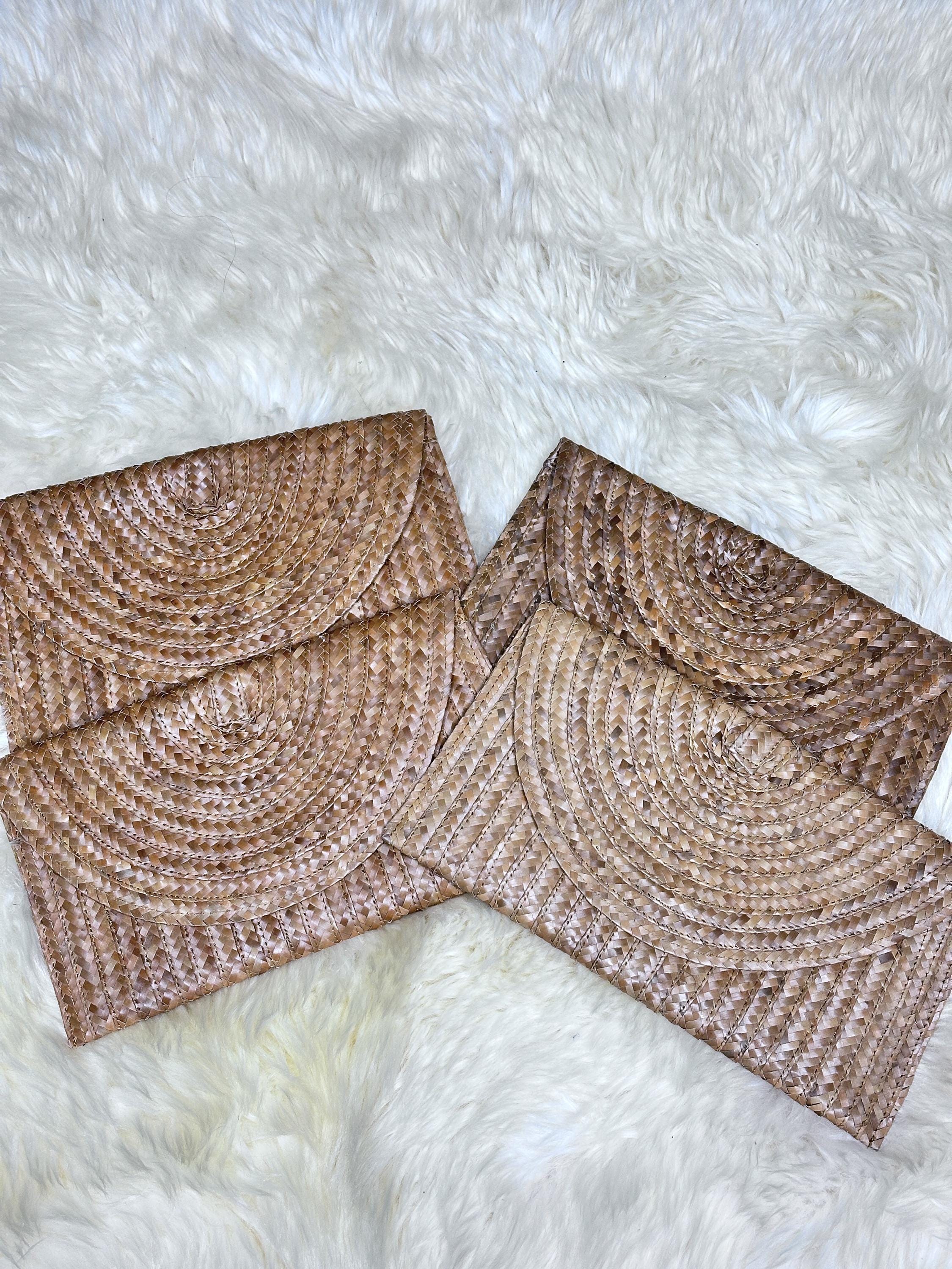 a close-up view of two brown woven purses or wallets placed on a white furry surface.