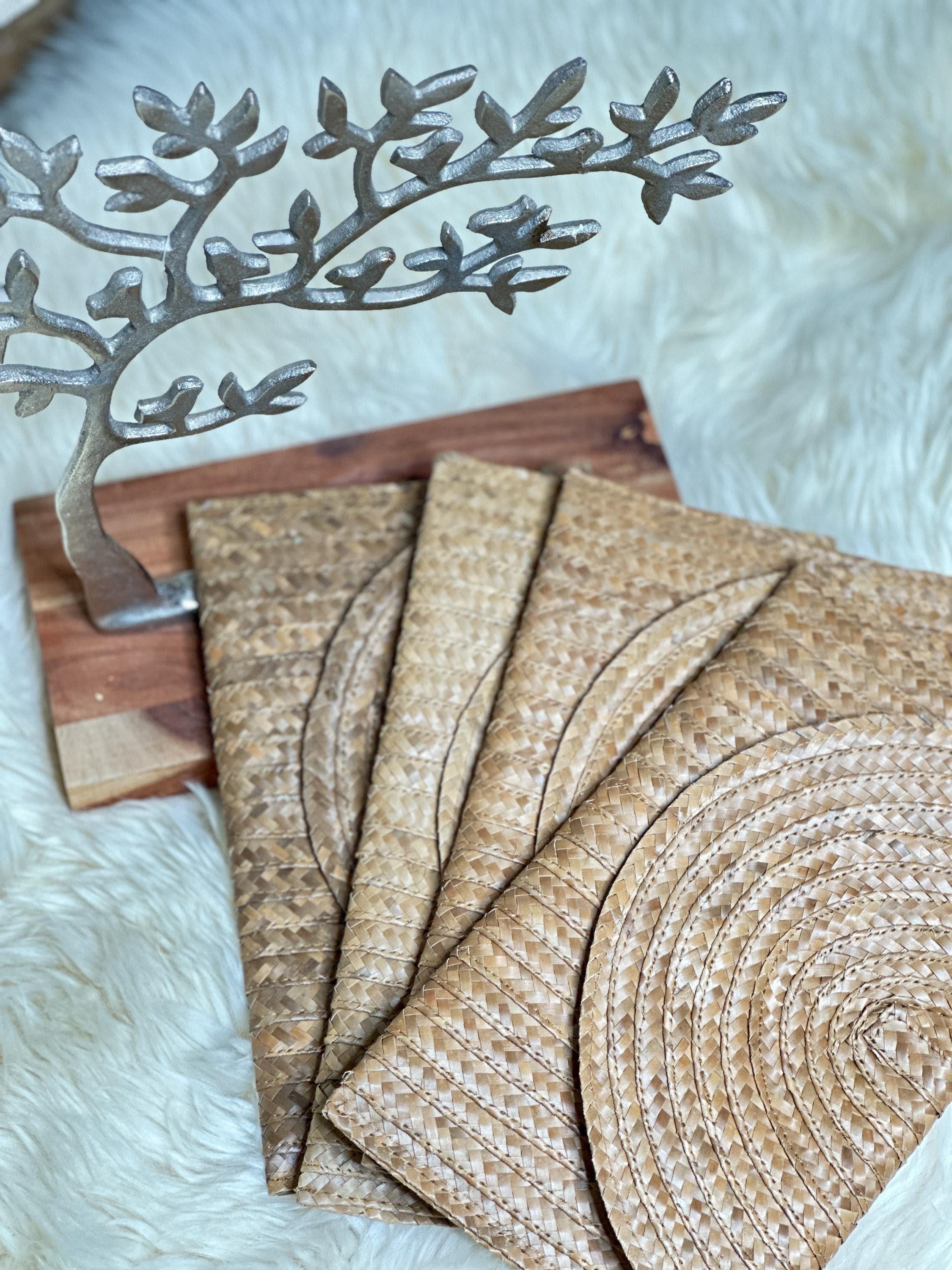 a wooden board with a decorative metal tree branch on top, and several woven straw bags or purses placed on a white fur surface.