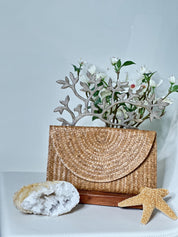 a woven purse, a bouquet of white flowers, a rock, and a starfish, all arranged on a white surface.