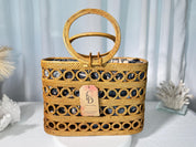 A woven handbag with a round handle and a tag displaying the letters 'CID' is displayed on a white surface.