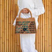A person wearing a white outfit is holding a woven handbag with a distinctive pattern.