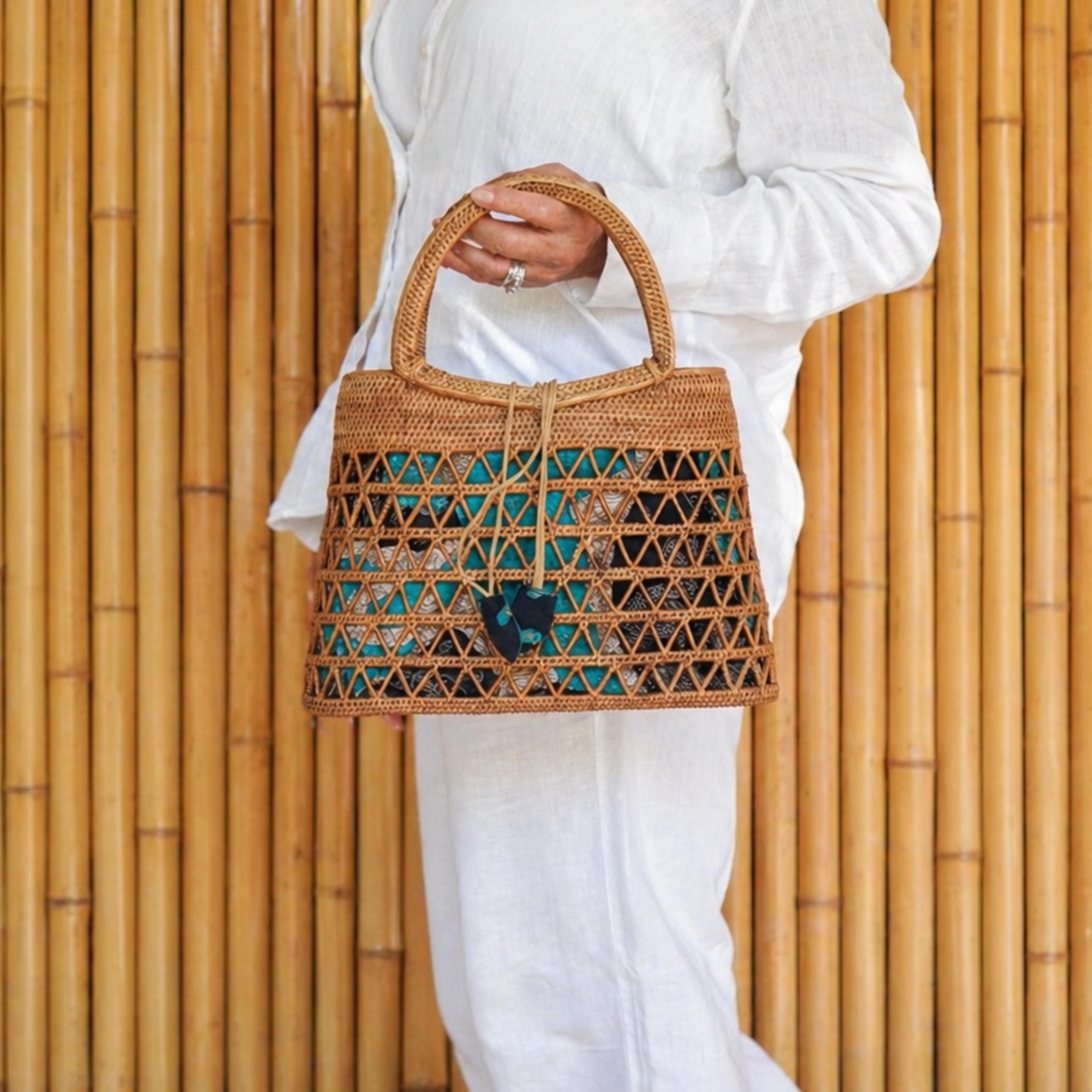 A person wearing a white outfit is holding a woven handbag with a distinctive pattern.