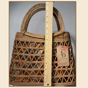 A woven handbag with a handle and a ruler placed next to it, indicating the size of the bag.